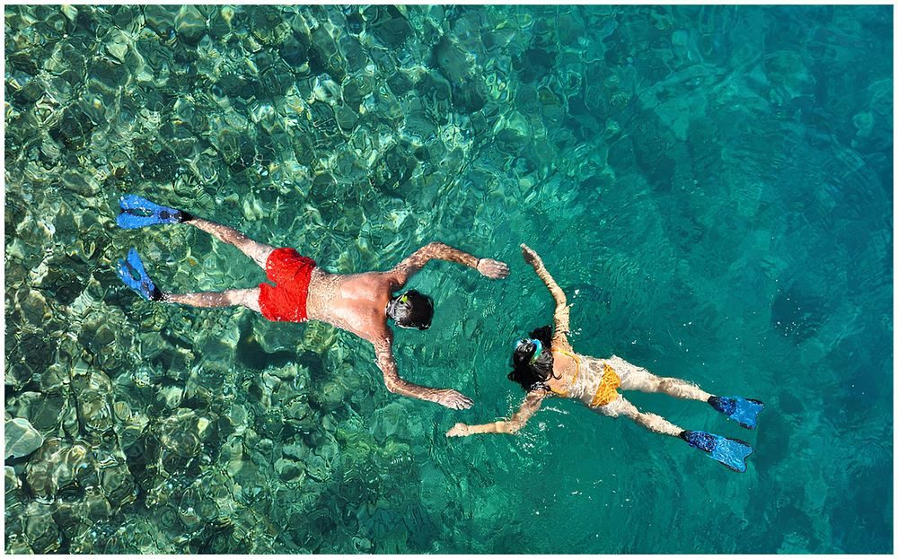Calm turquoise sea seen from above with two snorkelers