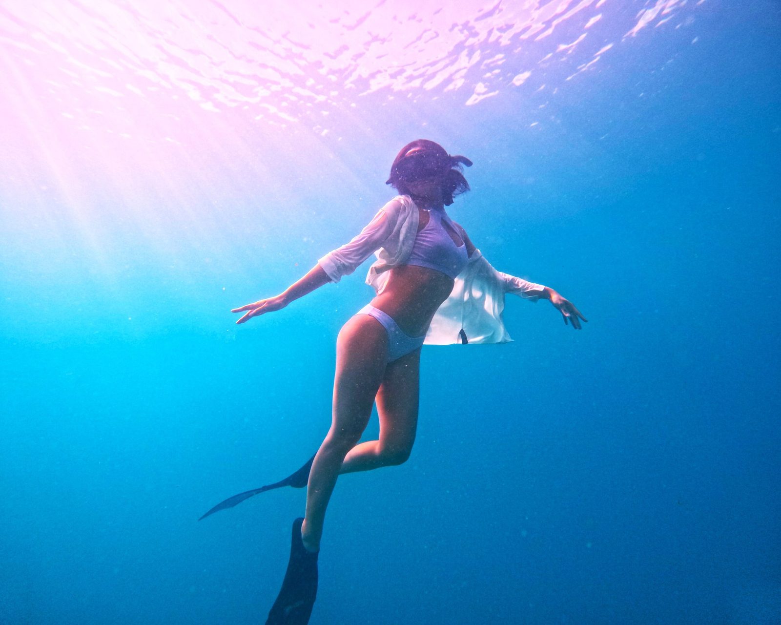 A snorkeler in deep blue water with sunlight from above