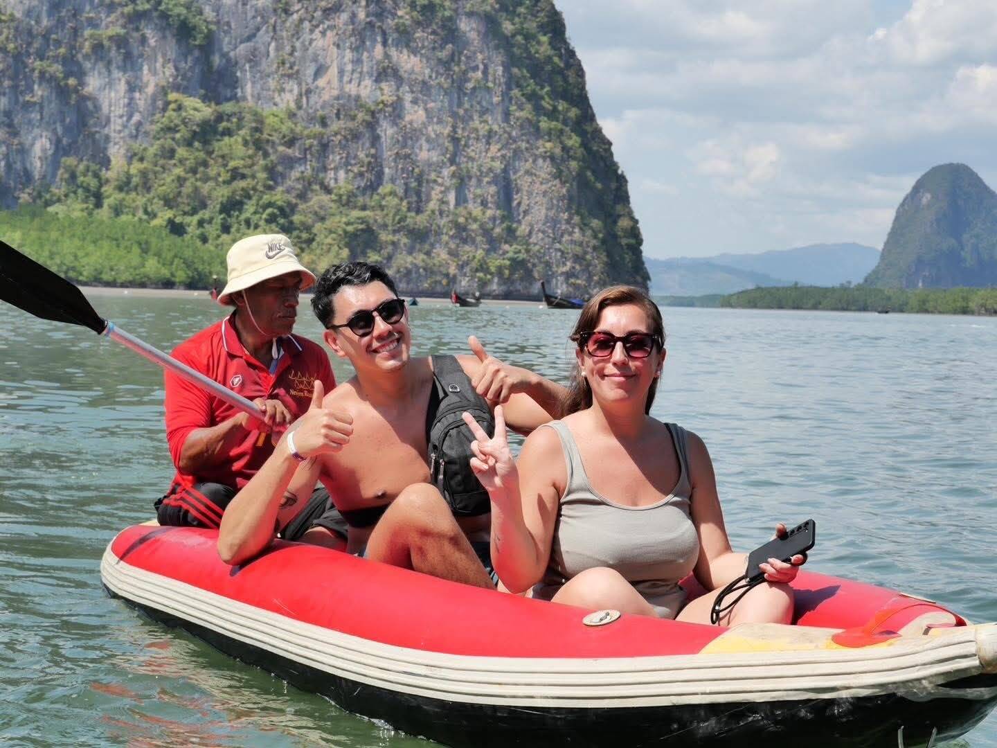 Guests giving a thumbs up on a sea cave canoe with limestone cliffs behind