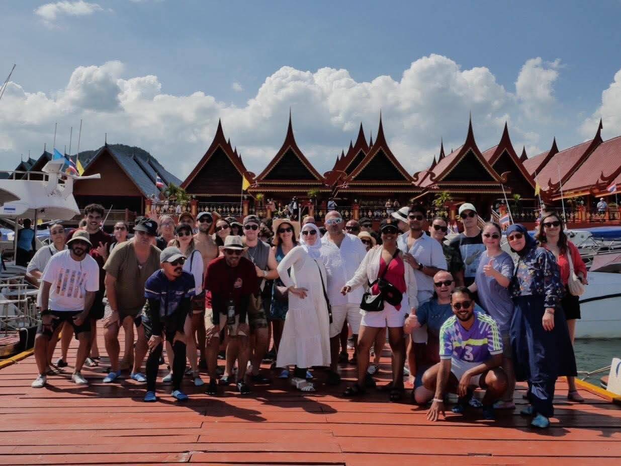 Tour group photo at the pier in front of Thai-style pavilion roofs