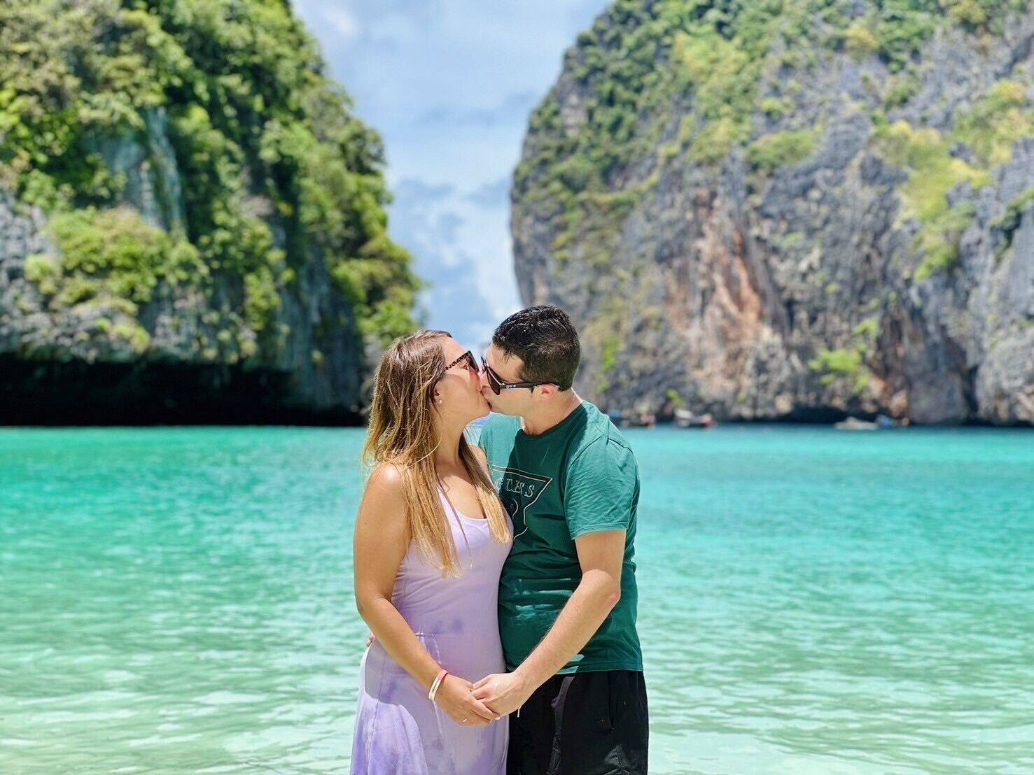 A couple in the water in front of Phi Phi's limestone cliffs