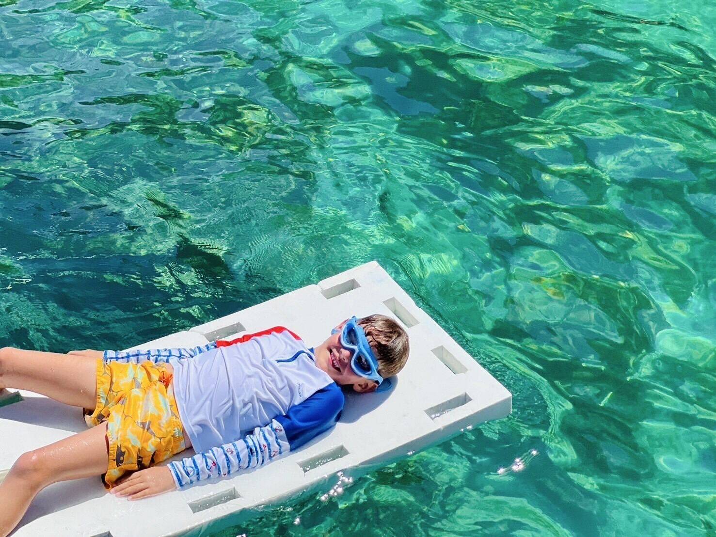 A child relaxing on a floating mat in the clear water at Phi Phi