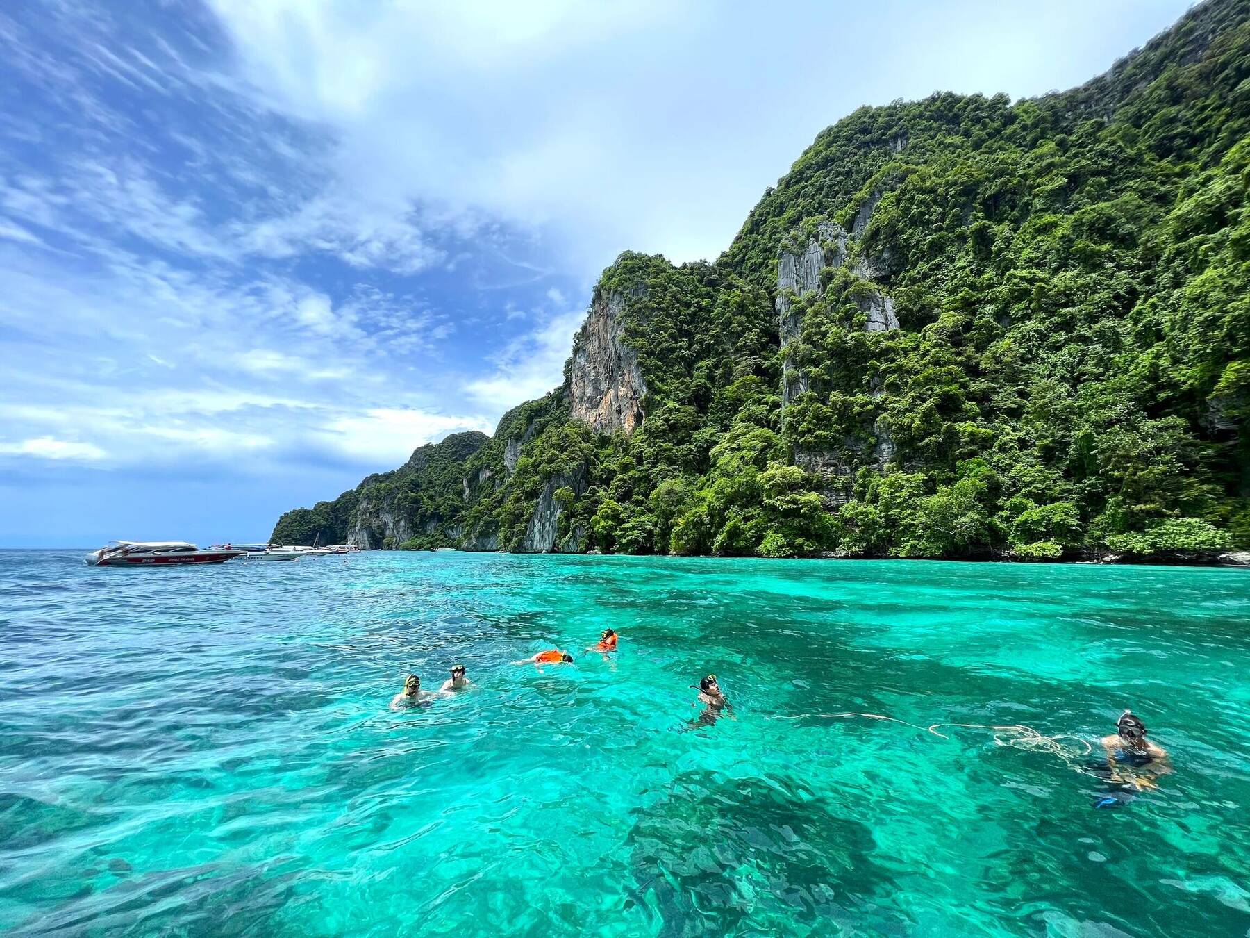 Guests in life vests snorkeling near the boats at Phi Phi
