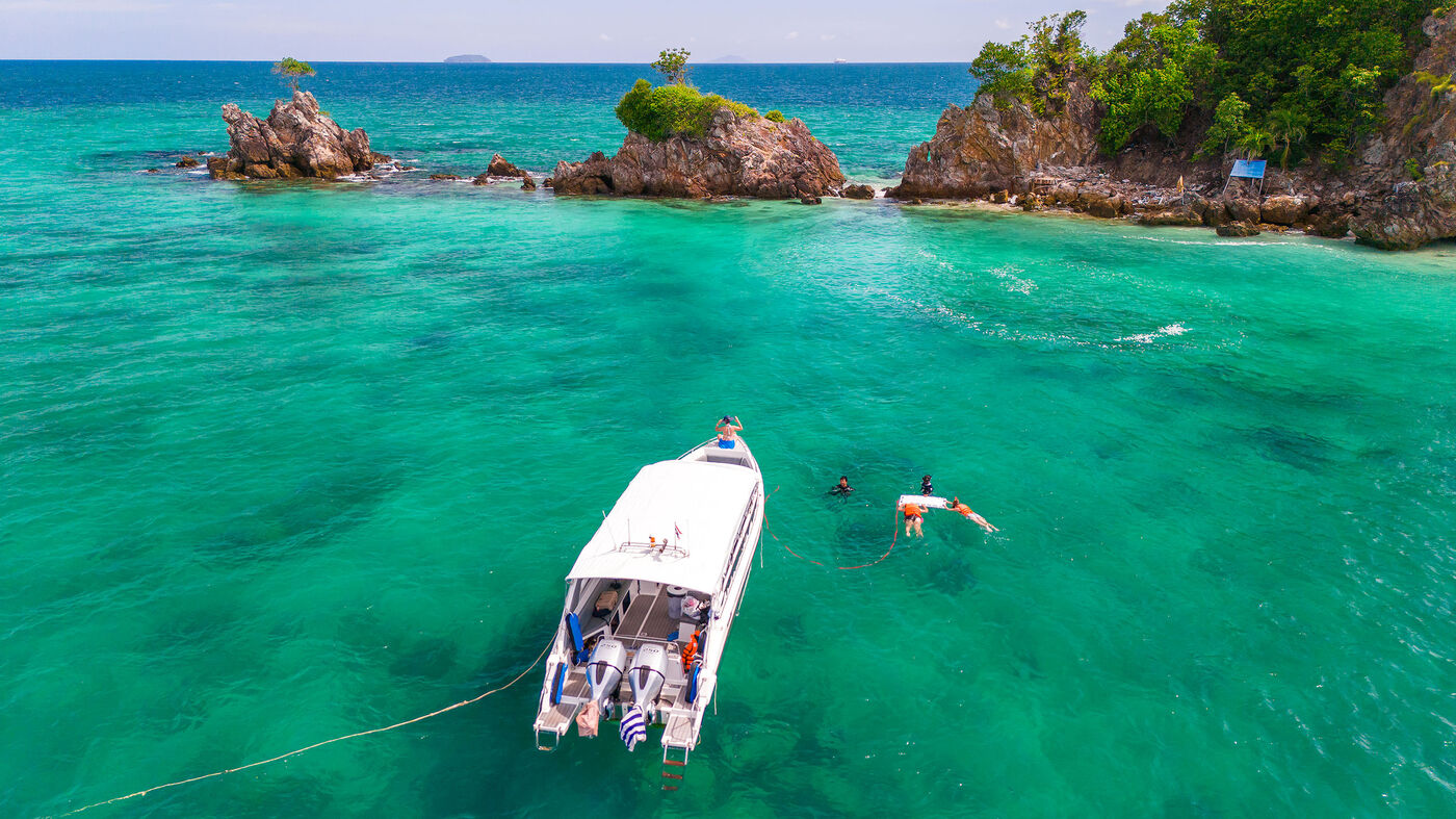 Speedboat and snorkelers in the turquoise water near Khai Islands