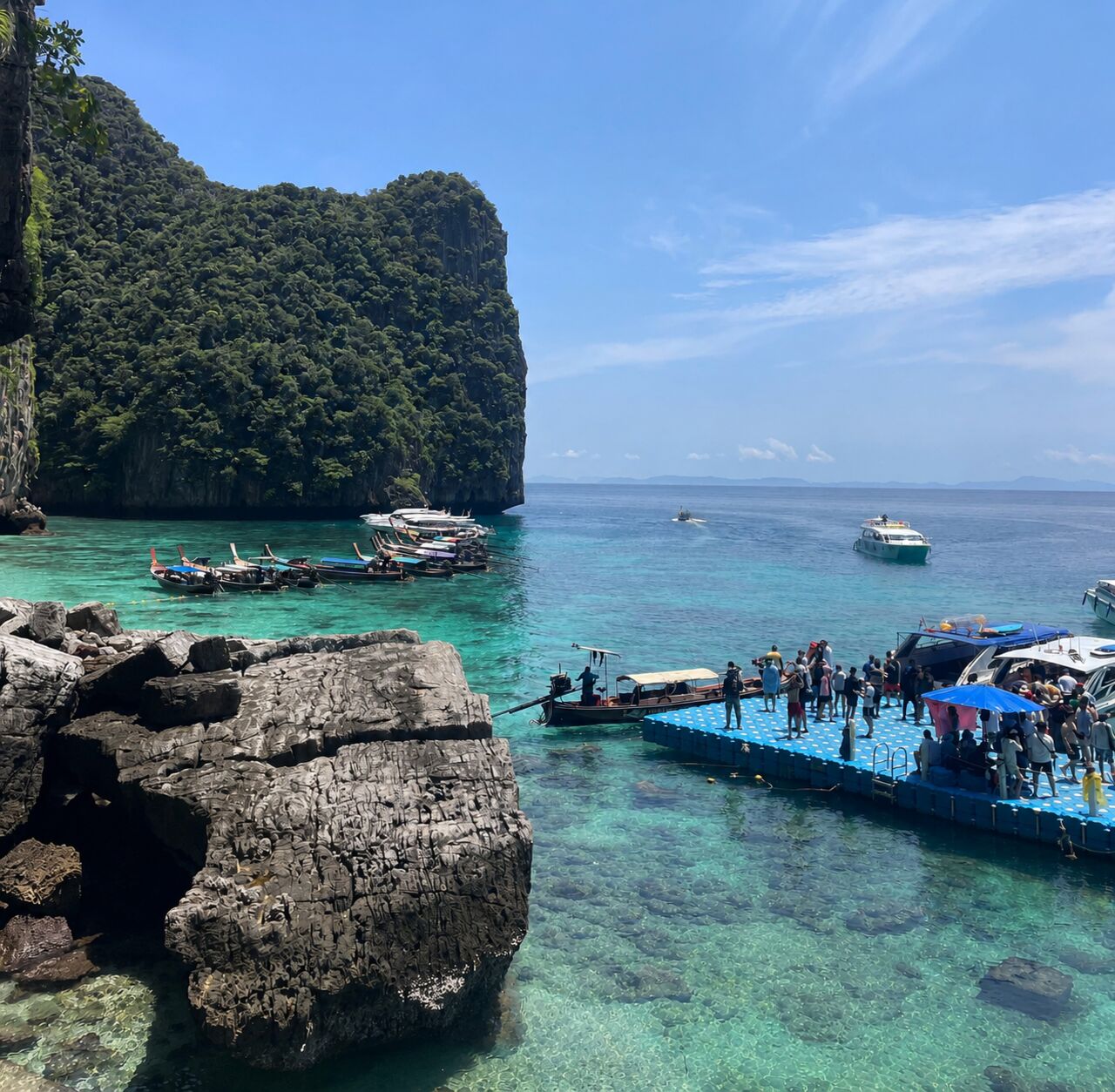 Longtail boats and floating dock at Phi Phi Island's limestone cliffs